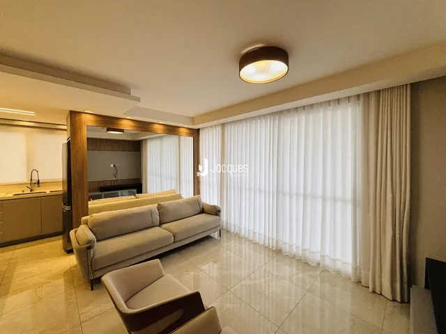 Sala de estar com sofá e grandes janelas iluminadas.