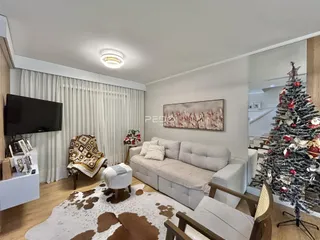 Sala de estar com sofá claro, poltronas e piso de madeira em um imóvel no Brasil.