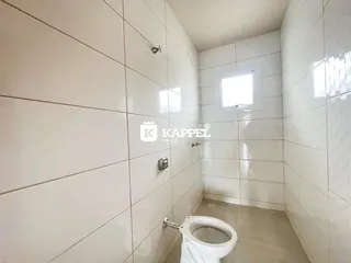 Banheiro com paredes revestidas em azulejos brancos e vaso sanitário branco.