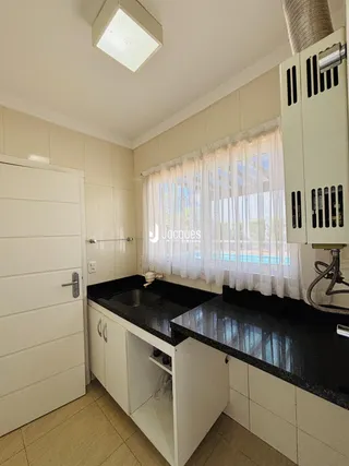 Interior de uma cozinha com armários brancos e bancadas escuras.