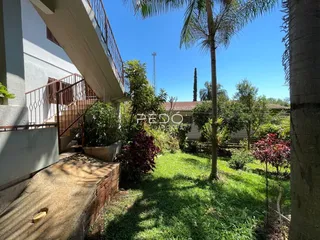 Vista externa de uma residência com jardim e vegetação.