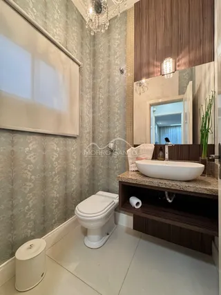 Foto de um banheiro interno com revestimento de papel de parede e bancada de madeira.