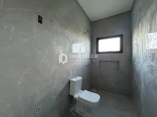 Foto de um ambiente interno com paredes de concreto aparente e um vaso sanitário.