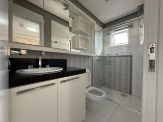 Banheiro moderno com bancada escura e box de vidro.