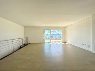 Ambiente interno de uma sala ampla com vista para o exterior.