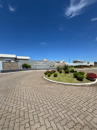 Vista externa da propriedade mostrando a entrada pavimentada e paisagismo.