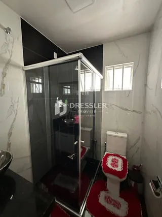 Foto de um banheiro com box de vidro e vaso sanitário.