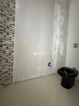 Foto de um banheiro com revestimento cerâmico e vaso sanitário preto.