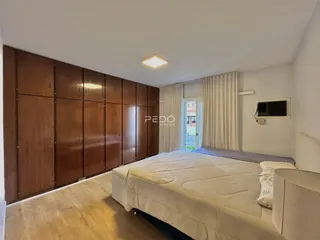 Quarto com armários em madeira e cama de casal.