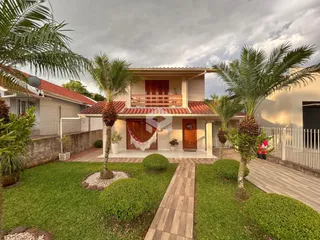 Vista da fachada de uma casa em Lajeado, Brasil, com jardim e palmeiras.