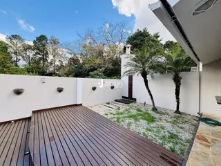 Uma vista da fachada de uma propriedade com deck de madeira e jardim.