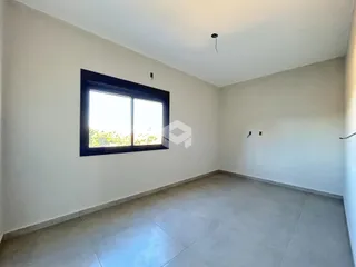 Ambiente interno de uma sala com grande janela e piso de cerâmica.