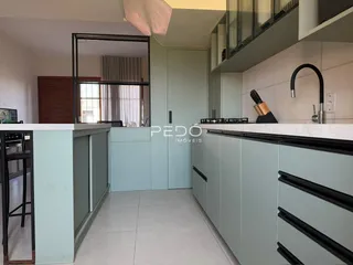 Cozinha moderna com armários verdes e bancadas brancas.