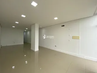 Vista interna de um espaço amplo com piso claro e paredes brancas.