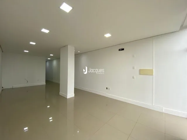 Vista interna de um espaço amplo com piso claro e paredes brancas.