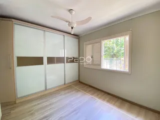 Ambiente interno de uma sala com piso de madeira clara e grandes portas de vidro.