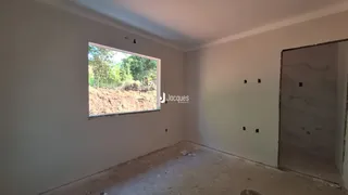 Vista de uma janela em uma sala de estar com paredes brancas e piso de concreto.