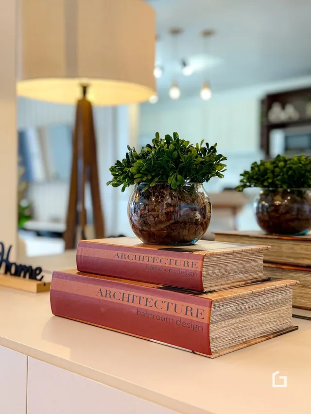 Foto de um interior com livros e uma luminária decorativa.