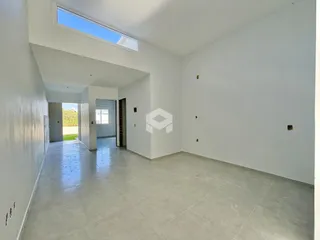 Ambiente interno de uma sala ampla com teto alto e grande janela.