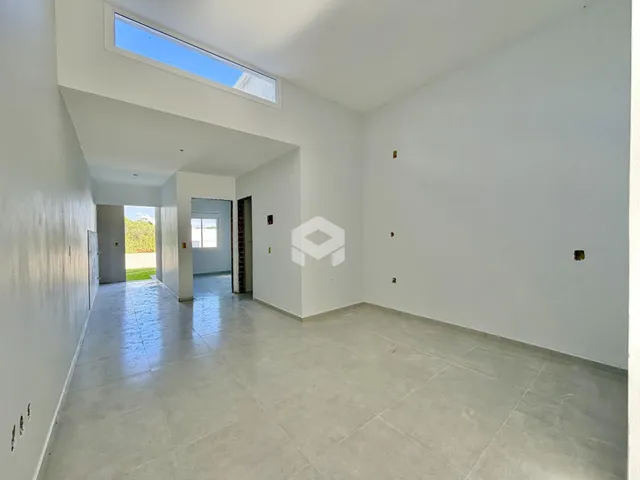 Ambiente interno de uma sala ampla com teto alto e grande janela.