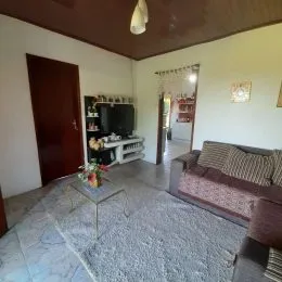 Foto interna de uma sala de estar com sofá e televisão.