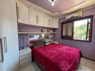Quarto com cama e armários brancos em ambiente com paredes roxas.