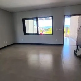 Foto de um ambiente interno vazio com piso claro e vista para o exterior.