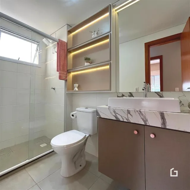 Foto interna de um banheiro moderno com revestimento de azulejo branco e bancada de mármore.