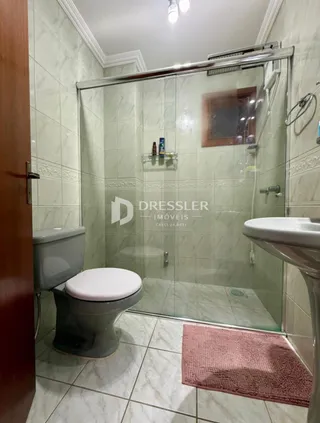 Foto interna de um banheiro com piso cerâmico e box de vidro.