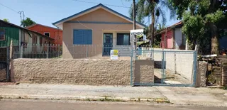 Fachada de uma residência em Lajeado, Brasil, com muro de pedra e cerca de metal.