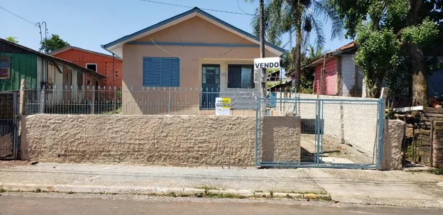 Fachada de uma residência em Lajeado, Brasil, com muro de pedra e cerca de metal.