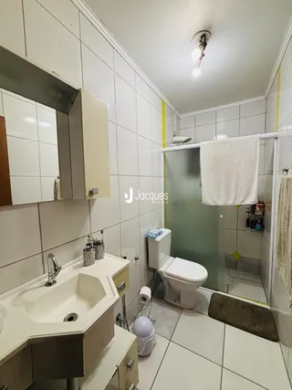 Foto interna de um banheiro com revestimento cerâmico branco.