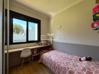 Quarto com janela grande e piso de madeira.