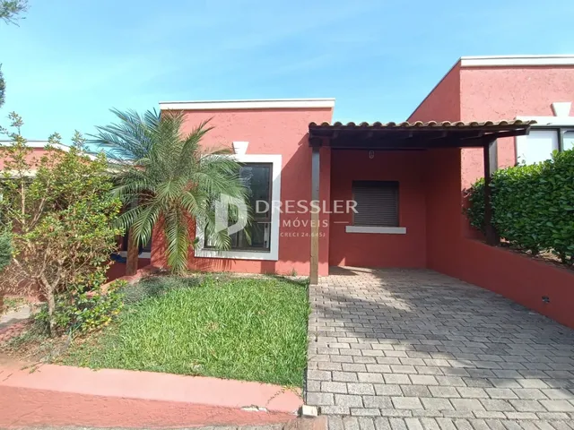Vista externa de uma residência com parede vermelha e jardim gramado.