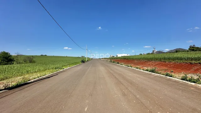 Uma estrada longa atravessa campos abertos sob um céu azul.