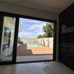 Sala de estar com grandes portas de vidro que dão vista para a área externa com piscina.