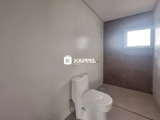 Foto de um banheiro com vaso sanitário branco e revestimento de parede claro.