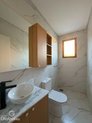 Foto de um banheiro com revestimento em mármore branco e louças sanitárias brancas.