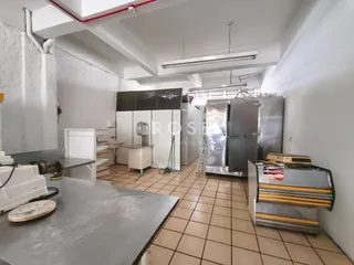 Cozinha comercial com equipamentos de aço inoxidável e piso cerâmico.