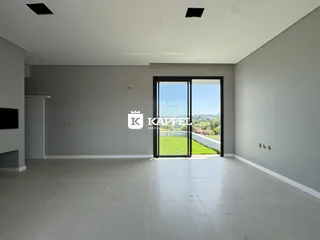 Sala ampla e moderna com piso claro e porta de vidro com vista para a área externa.