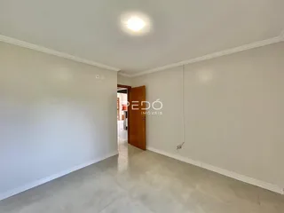 Vista de um corredor interno com paredes brancas e piso claro.