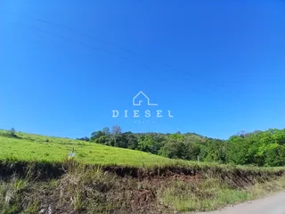 Paisagem de colinas verdes e vegetação densa sob um céu azul claro.