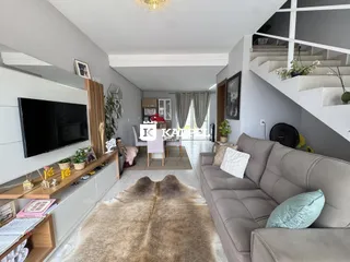 Sala de estar com sofá grande e televisão montada na parede.