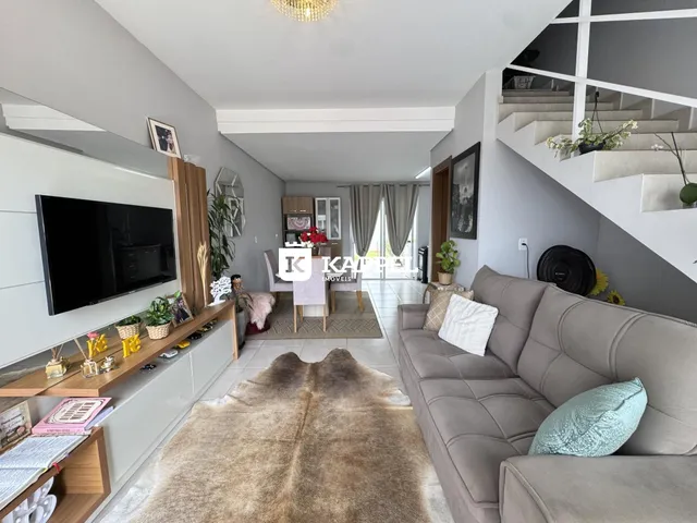 Sala de estar com sofá grande e televisão montada na parede.