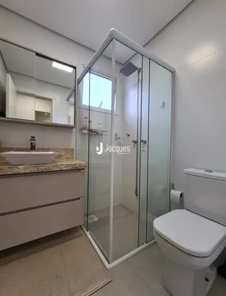 Foto de um banheiro com box de vidro e louças sanitárias.