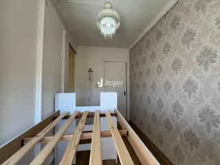 Hall de entrada com papel de parede ornamentado e piso de madeira.