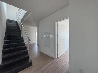 Hall de entrada com escadaria e piso de madeira.