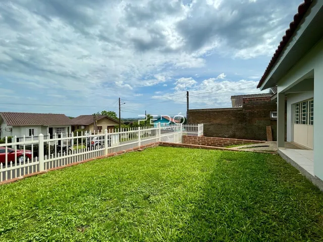 Vista da fachada de uma residência com jardim gramado e cerca branca.