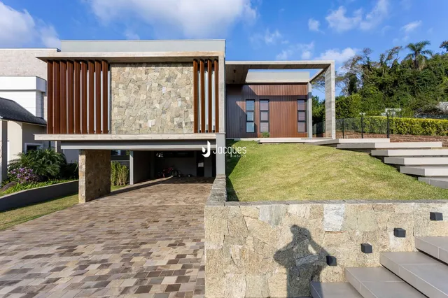 Fachada moderna de uma residência em Lajeado, Brasil, com jardim e muro de pedra.