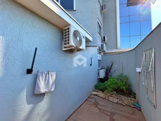 Vista externa da parede de uma residência em Lajeado, Brasil, mostrando unidades de ar-condicionado e um jardim.